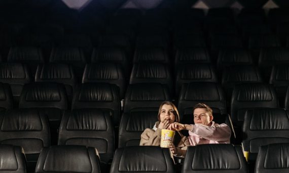 A couple enjoying a movie date with popcorn in an empty theater.